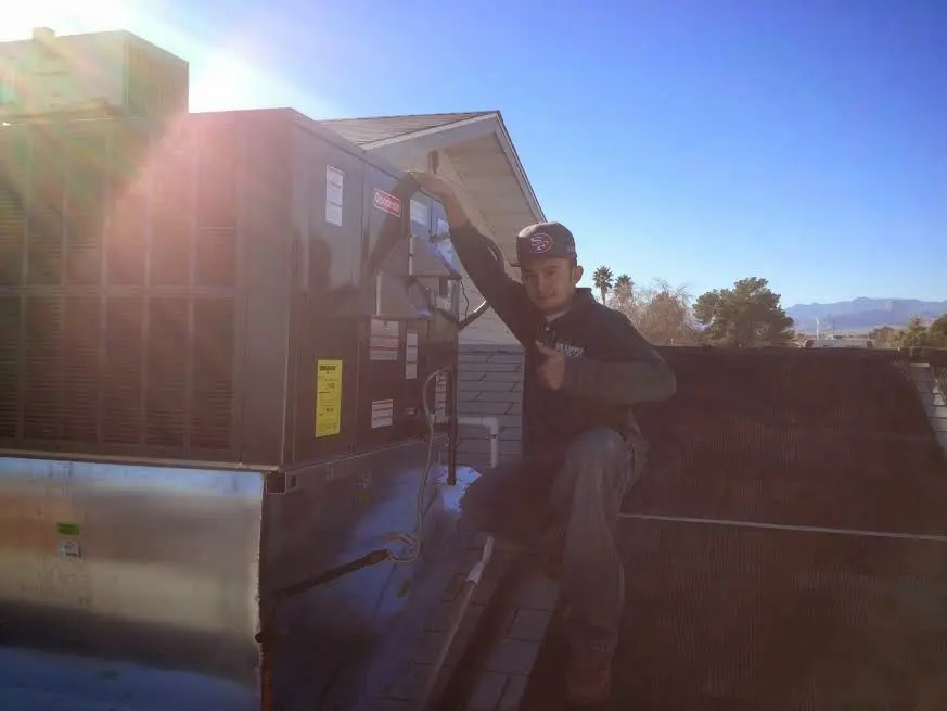 HVAC technician performing AC Tune-Up on a rooftop unit in Genesee