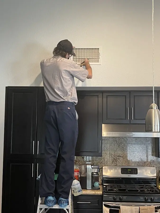 Technician inspecting an air vent during HVAC service in Genesee